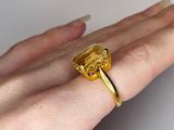 a woman ' s hand holding a ring with a yellow stone on it