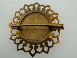 an image of a gold brooch with a coin in the middle of it
