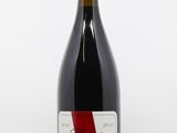 a bottle of red wine sitting on top of a white table