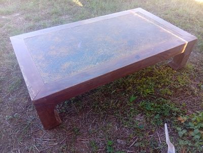 une table basse avec un plateau en verre posée dans l'herbe