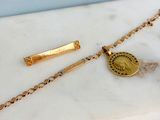 un gros plan d'un collier en or orné d'une pièce de monnaie, posé sur une surface en marbre