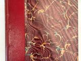 un vieux livre à la couverture rouge posé sur une table blanche