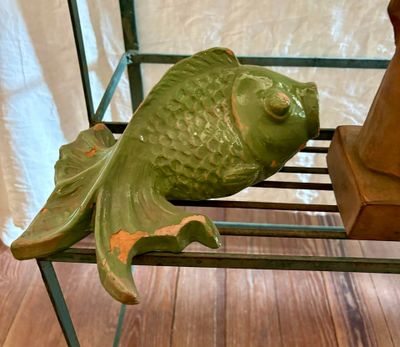 une statue représentant un poisson posée sur une étagère à côté d'un vase