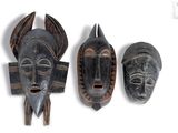 three african masks are displayed on a white surface