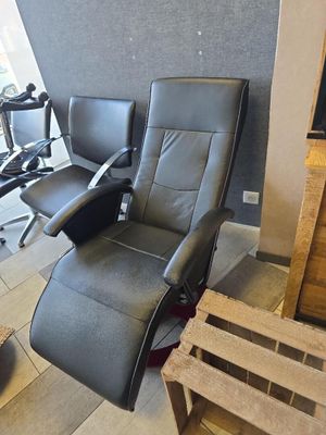 deux fauteuils inclinables dans une pièce où une télévision est accrochée au mur