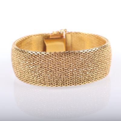 gros plan d'un bracelet en or sur une surface blanche