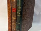 trois livres sont empilés sur une surface blanche