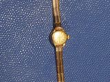 a blue purse with a gold watch on it