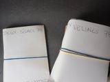 two pieces of paper with writing on them sitting on a table