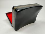 an image of a black box with a red lid on a white surface