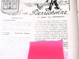 a pink post it on top of a book with a sticker on it