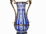 un vase bleu et blanc posé sur un socle, sur une surface blanche