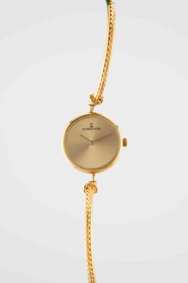 a close up of a gold wrist watch with a chain around it
