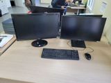 two computer monitors sitting on a desk with a keyboard and mouse