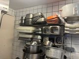many pots and pans stacked on a shelf in a kitchen