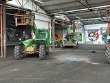deux tracteurs garés à l'intérieur d'un bâtiment, avec un homme à l'arrière d'un tracteur