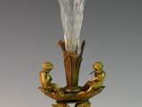 a glass vase on a stand with two birds on it