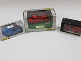 trois camions miniatures dans une boîte posée sur une surface blanche