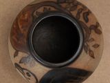 a small vase with a bird on it on a table