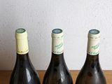 four bottles of wine are lined up on a wooden table