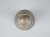 a silver and gold button on a white surface