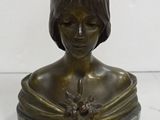 bronze bust of a woman with a flower in her hair