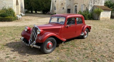 an old red car parked in front of a church