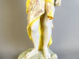 une statue représentant un homme debout sur un socle en marbre