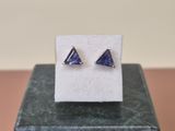 une paire de boucles d'oreilles en saphir bleu de forme triangulaire posées sur un bloc de marbre