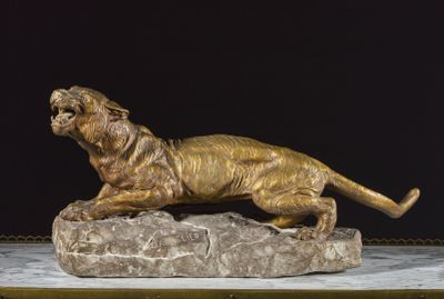 bronze statue of a tiger on a rock on a black background