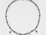 a close up of a necklace with blue and white stones on a white surface