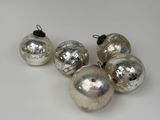 quatre boules de Noël en verre argenté posées sur un fond blanc