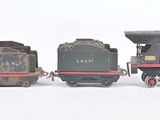 quatre petits trains miniatures posés les uns à côté des autres sur une surface blanche