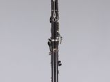 a black and silver clarinet on a white surface with a gray background