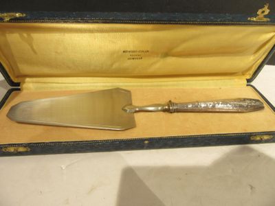 un couteau à gâteau en argent dans un étui posé sur une table
