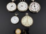Plusieurs modèles différents de montres de poche sont exposés sur un fond noir