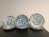 trois assiettes en porcelaine bleues et blanches posées sur une table noire