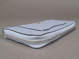 silver zippered purse on a gray surface with a chain around it