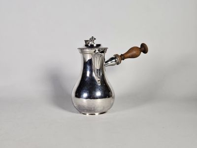 une cafetière en argent avec une poignée en bois sur une surface blanche