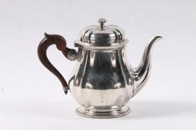 une théière ancienne en argent avec une anse en bois, sur fond blanc