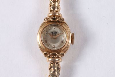 une montre en or entourée d'une chaîne sur une surface blanche