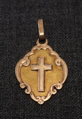 un gros plan d'une croix sur un pendentif en or posé sur un tissu noir