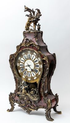 une horloge posée sur un support sur une surface blanche