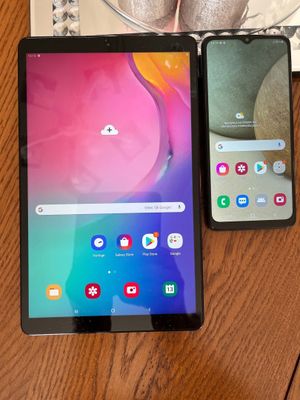 two samsung galaxy tabs sitting on a table next to a cup of coffee