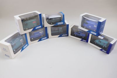 six boîtes contenant des modèles réduits de voitures bleues et blanches, posées sur une surface blanche