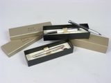 trois stylos dans une boîte posée sur une table, dans laquelle se trouve un stylo