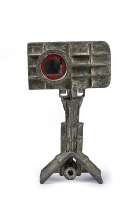 a small metal object with a red eye on top of it