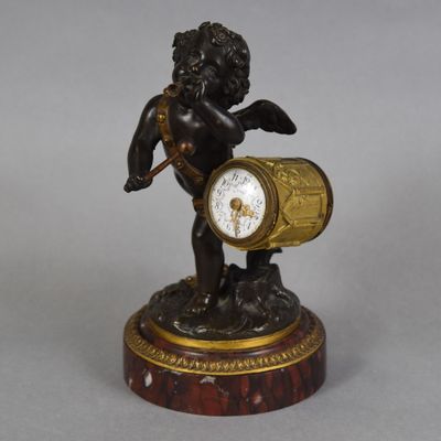 a statue of a cupid holding a clock on a table
