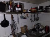 many pots and pans hanging on the wall above the sink