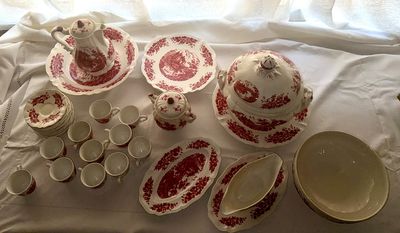 a lot of red and white dishes and cups on a table